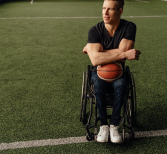 Man in rolstoel met een basketbal op schoot